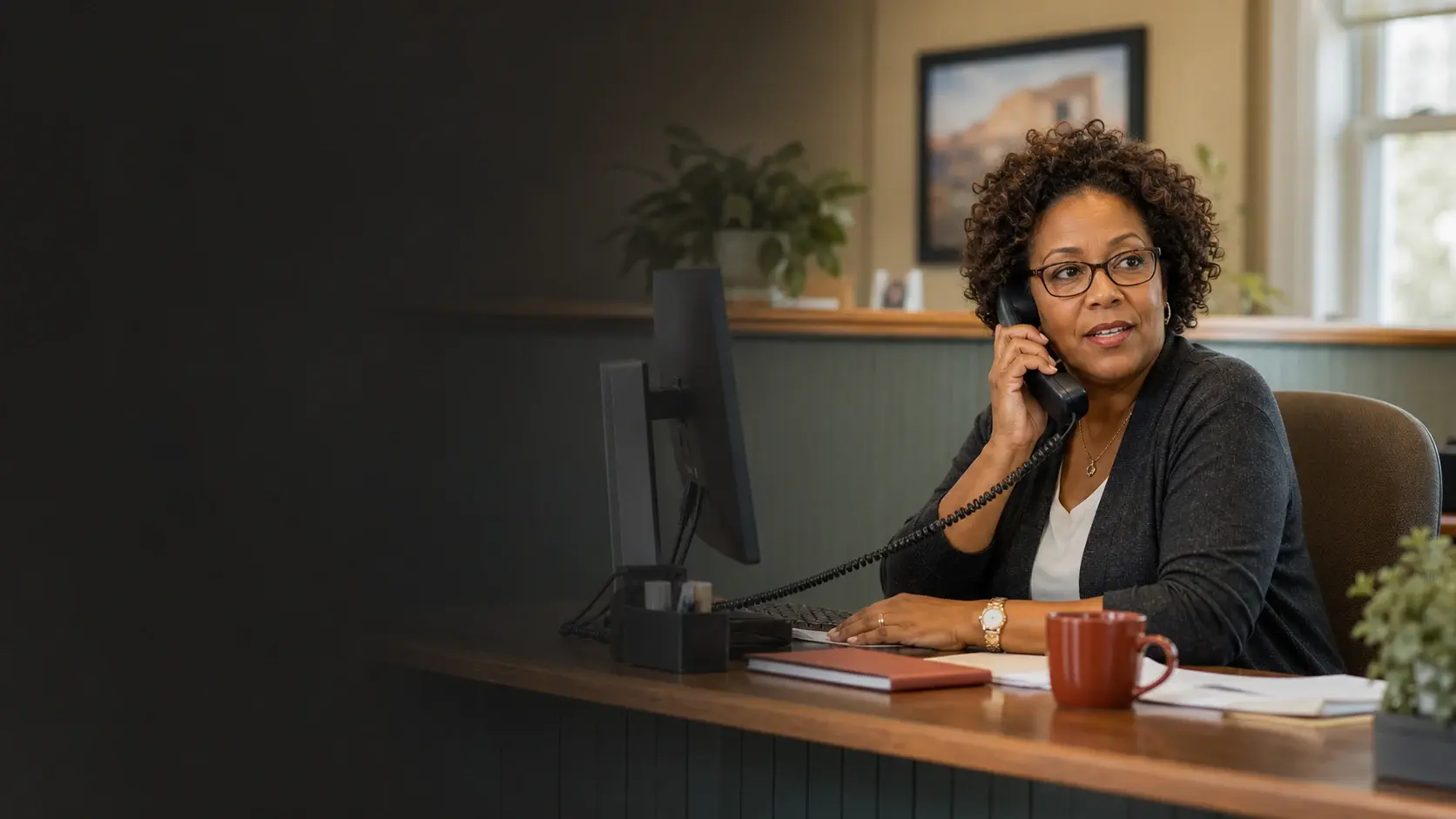 An insurance office receptionist managing a customer call from her desk