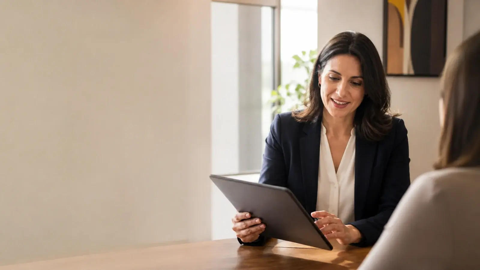 Professional adviser reviewing a presentation on a tablet with a client in a modern office